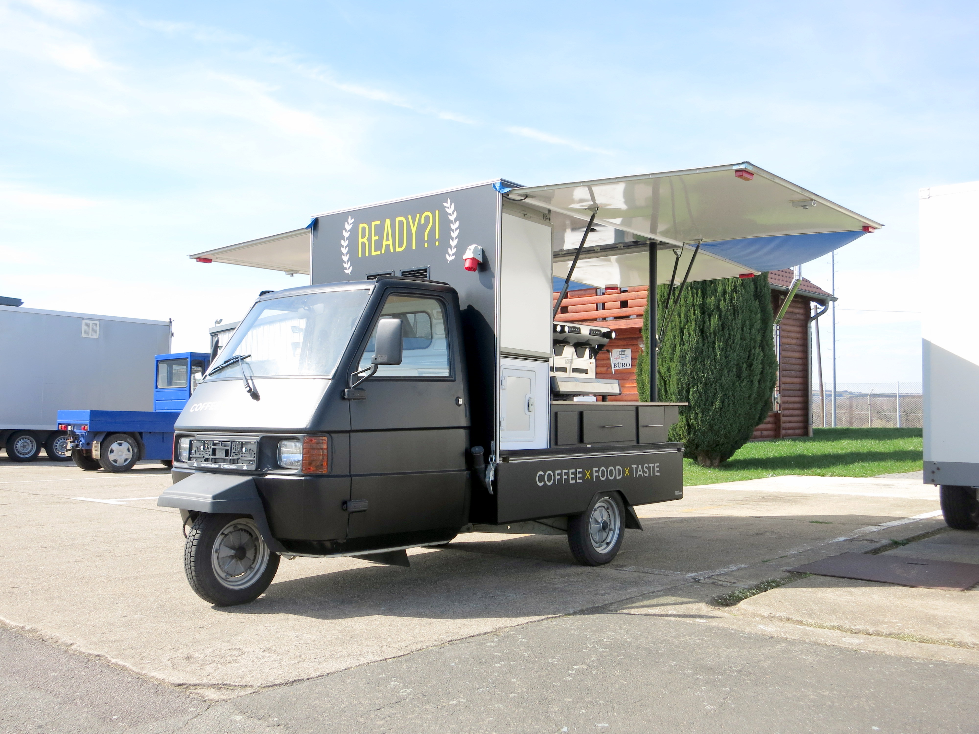 Piaggio Ape nach dem Umbau - eleganter schwarzer READY Coffee Truck mit Markise
