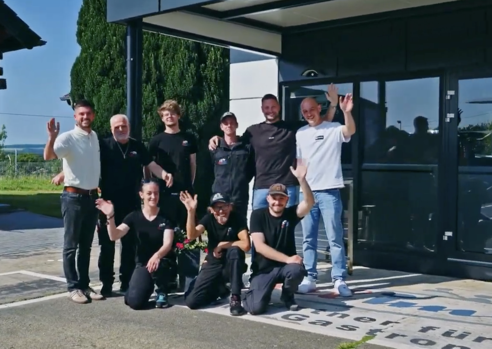 Das Eifelimbiss Team winkt vor dem Firmengebäude in Brimingen - Familienunternehmen mit über 25 Jahren Erfahrung im Food Truck Umbau